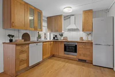 a kitchen with wooden cabinets and a white refrigerator at Large Historic Apartment in the best part of Bergen in Bergen