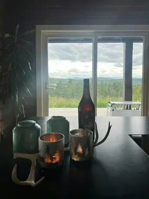 a bottle of wine and candles on a table with a window at Mountain Cabin With Great Ski Terrain in Vingelen
