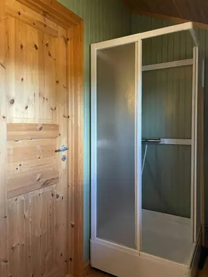 a glass shower in a room with a wooden wall at Modernized Log Cabin At Ljøsheim in Sjusjøen