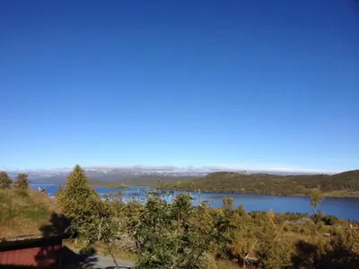 a view of a lake with a house and trees at Authentic Cabin Overlooking Lake Møsvann in Rjukan