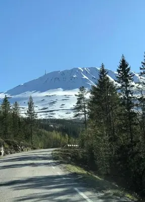 an empty road with a snow covered mountain in the background at Authentic Cabin Overlooking Lake Møsvann in Rjukan