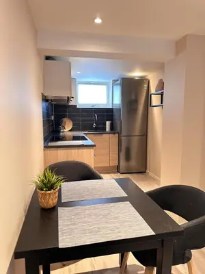 a kitchen with a table and a stainless steel refrigerator at Free parking grand floor Apartment in Ålesund in Ålesund