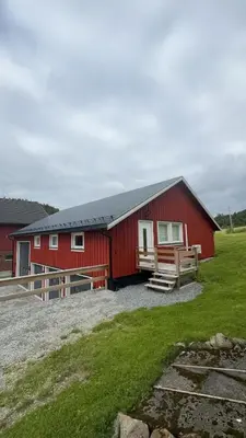 a red barn with a grass field next to it at Steinkjer, 5 room apartment in Steinkjer