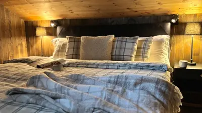 a bedroom with a large bed with a wooden wall at Modern and cozy mountain cabin - panoramic view! in Torvetjørn