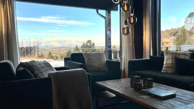 a living room with a table and chairs and a large window at Modern and cozy mountain cabin - panoramic view! in Torvetjørn