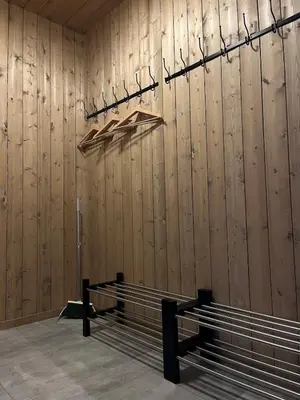 a room with a wooden wall with a bench and hangers at Modern and cozy mountain cabin - panoramic view! in Torvetjørn