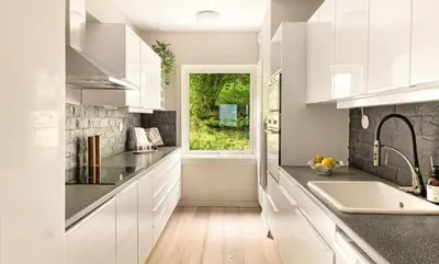 a kitchen with white cabinets and a window at Solheimslien in Bergen