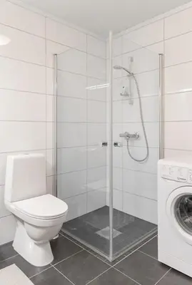 a bathroom with a toilet and a shower and a washing machine at Mountain Dream in Vossevangen