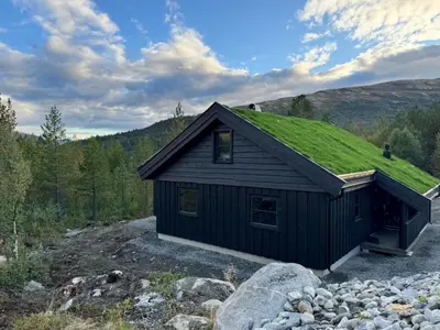 a black house with a grass roof on a hill at Elegantes, ruhiges Ferienhaus in bester Lage für alle Outdoorfans in Randsverk