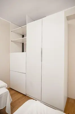 a bedroom with white cabinets and a bed at Leiligheter i sentralt Bergenshus in Bergen