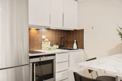 a kitchen with white cabinets and a stove top oven at Leiligheter i sentralt Bergenshus in Bergen