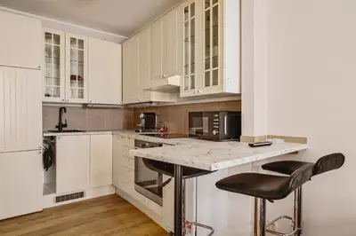 a kitchen with white cabinets and two bar stools at Leiligheter i sentralt Bergenshus in Bergen