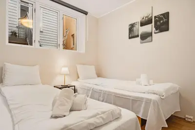a room with three beds with white sheets and a window at Leiligheter i sentralt Bergenshus in Bergen