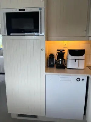 a kitchen with a white refrigerator and a microwave at Stor hytte med praktfull havutsikt in Lysøysund