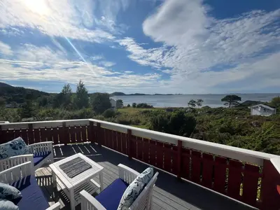 a deck with chairs and a table and a view of the ocean at Stor hytte med praktfull havutsikt in Lysøysund