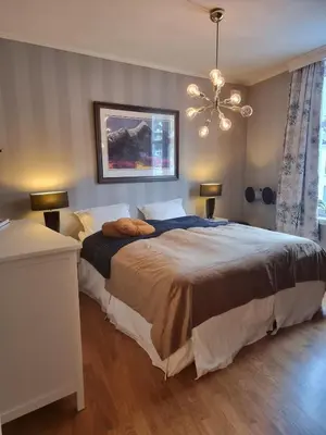 a bedroom with a large bed and a chandelier at Central, lovely apartment with a unique view in Bergen