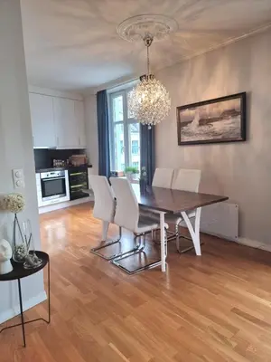 a dining room with a table and white chairs at Central, lovely apartment with a unique view in Bergen