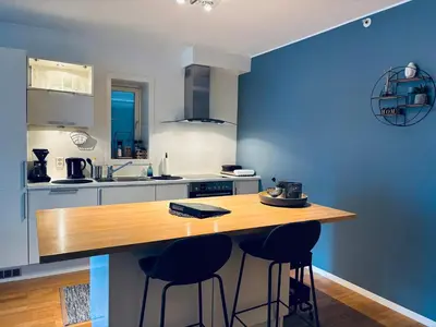 a kitchen with blue walls and a wooden counter with stools at Central Apt - Steps to Fish Market and Bryggen in Bergen