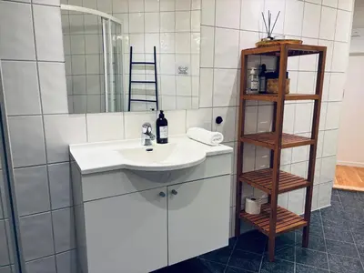 a white bathroom with a sink and a shelf at Central Apt - Steps to Fish Market and Bryggen in Bergen