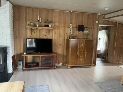 a living room with a television on a wooden wall at Home with a view in Lom