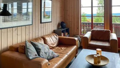 a living room with a brown leather couch and two chairs at Cosy Cabin By Golsfjellet Ski Resort in Gol