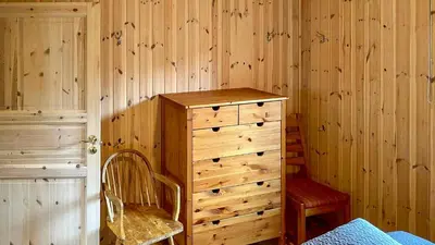 a bedroom with a wooden wall with a dresser and a chair at Cosy Cabin By Golsfjellet Ski Resort in Gol