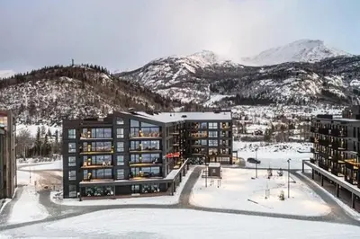 a building in the snow with mountains in the background at Ski out ski in Luxus Hemsedal in Hemsedal