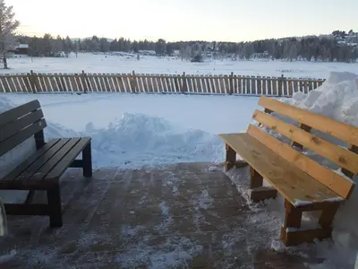 a wooden bench sitting next to a pool of snow at Kvamsfjellet - Rondane in Nord-Fron