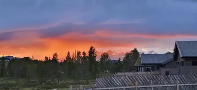 a rainbow in the sky over a house and trees at Kvamsfjellet - Rondane in Nord-Fron