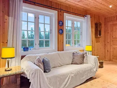 a living room with a couch and two windows at Mountain cabin in Aurdal Fireplace Sauna 1000 meters above sea level in Aurdal