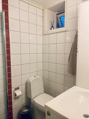 a white bathroom with a toilet and a sink at Central studio apartment in Bergen