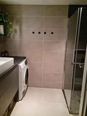 a bathroom with a shower and a washing machine at Flott leilighet mellom sjø og fjell in Bergen