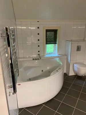 a white bathroom with a tub and a toilet at Mountain Retreat in Brattvg - Unwind in Nature in Brattvåg