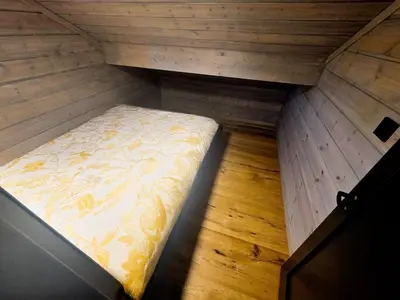 a small bed in a room with a wooden floor at Unique hytta with jacuzzi, sauna, 7 bedrooms in Trysil