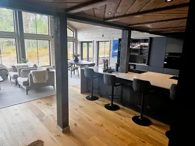 a kitchen and living room with a counter and chairs at Unique hytta with jacuzzi, sauna, 7 bedrooms in Trysil