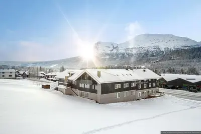 a house in the snow with a mountain in the background at Charming apartment with lodgefeeling in Hemsedal