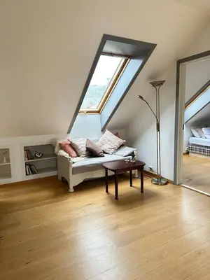 a living room with a couch and a window at Bright loft apartment in a Jugend-style building close to Brosund in Ålesund