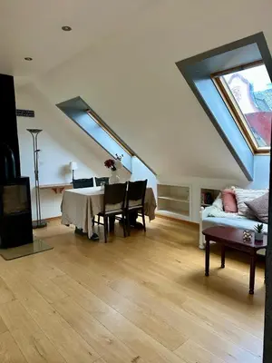a living room with a table and a couch at Bright loft apartment in a Jugend-style building close to Brosund in Ålesund