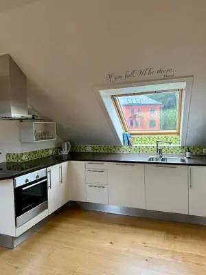 a kitchen with white cabinets and a large window at Bright loft apartment in a Jugend-style building close to Brosund in Ålesund