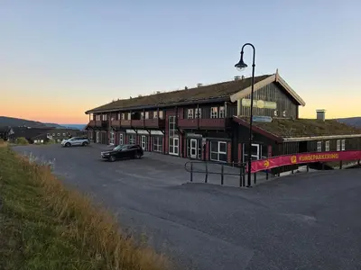 a building with a car parked in a parking lot at Fjellstolen apartment nr 12 in Beitostøl
