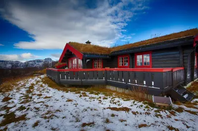 a house with a grass roof on a snow covered yard at Timber Cabin With Mountain View in Beitostøl