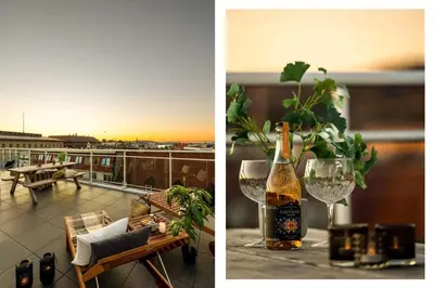 a bottle of wine and glasses on a table on a balcony at Torgalmenningen Town Square, Yet quiet, Elevator in building in Bergen