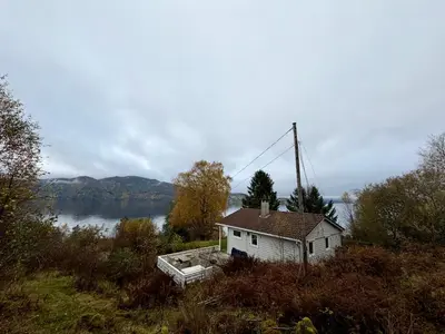 a small house sitting on the side of a lake at Fjordview retreat in Hamre