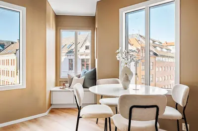 a dining room with a table and chairs and windows at Barfot Apartment - Bergen City center in Bergen