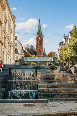 a fountain in front of a building with a clock tower at Barfot Apartment - Bergen City center in Bergen