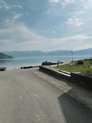 a road next to a beach with the ocean at Toppleilighet i sentrum av øystese in Kvam