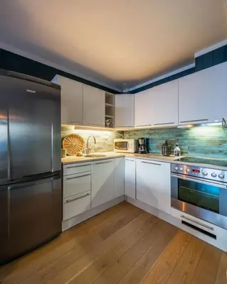 a kitchen with white cabinets and stainless steel appliances at Ski in-Ski out and True Mountain Charm in Hemsedal