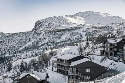 a resort in the snow with a mountain in the background at Ski in-Ski out with Style and Scenic Views in Hemsedal