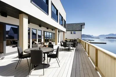 a deck with tables and chairs and a view of the water at Rosenlund Hamn in Sande