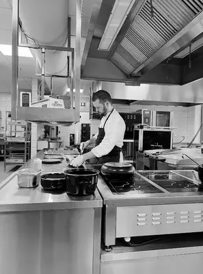 a man standing in a kitchen preparing food at Rosenlund Hamn in Sande